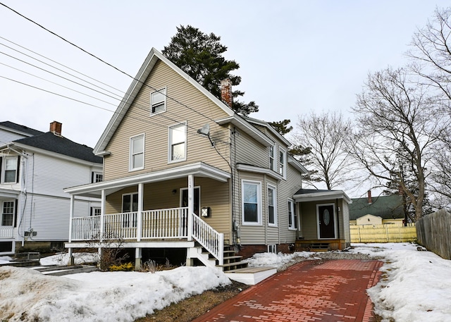 view of front of property featuring a porch, a chimney, and fence