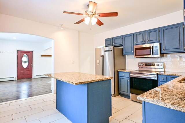 kitchen with a baseboard heating unit, blue cabinets, arched walkways, and appliances with stainless steel finishes