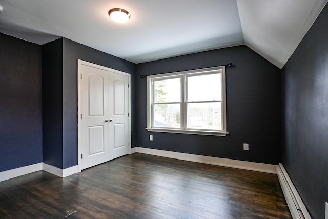 unfurnished bedroom with dark wood-style floors, baseboards, vaulted ceiling, a closet, and baseboard heating