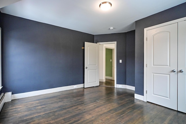 unfurnished bedroom with wood finished floors, baseboards, and a baseboard radiator