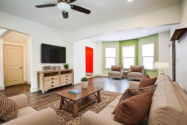 living area with baseboard heating, recessed lighting, arched walkways, and dark wood-style flooring