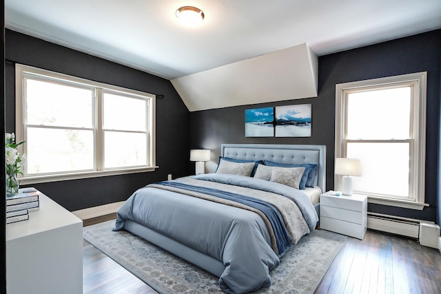 bedroom featuring a baseboard heating unit, baseboards, vaulted ceiling, and hardwood / wood-style flooring