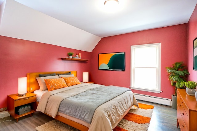 bedroom with a baseboard heating unit, wood finished floors, and vaulted ceiling