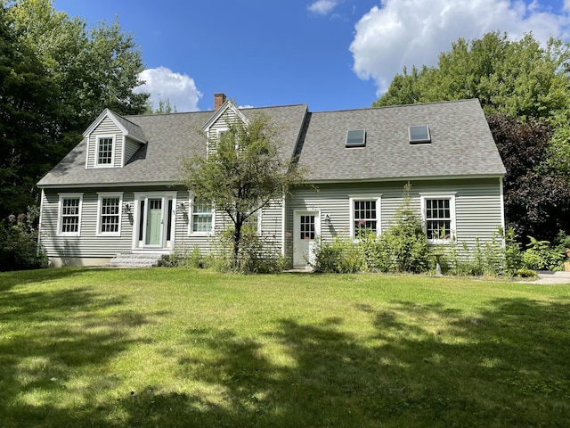 rear view of property featuring a chimney, a yard, and roof with shingles