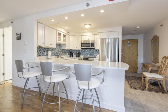 kitchen with a peninsula, a kitchen breakfast bar, tasteful backsplash, and stainless steel appliances