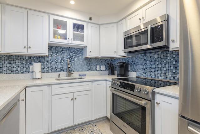 kitchen featuring tasteful backsplash, white cabinets, stainless steel appliances, and a sink