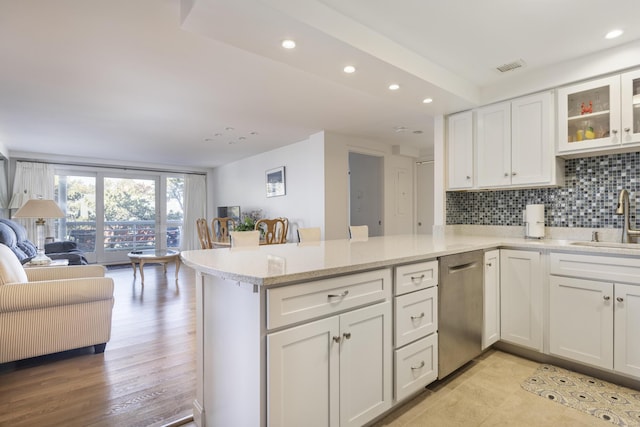 kitchen featuring white cabinetry, a peninsula, a sink, decorative backsplash, and dishwasher