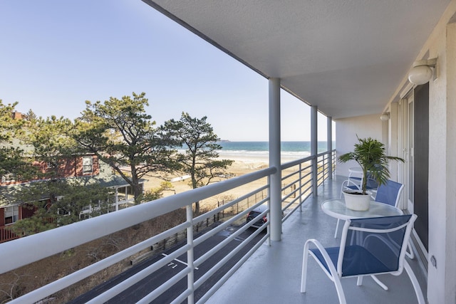 balcony featuring a view of the beach and a water view