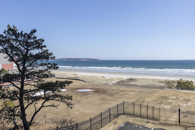 water view featuring fence and a beach view