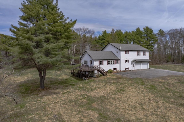 back of house with aphalt driveway, stairway, a wooden deck, a yard, and an attached garage