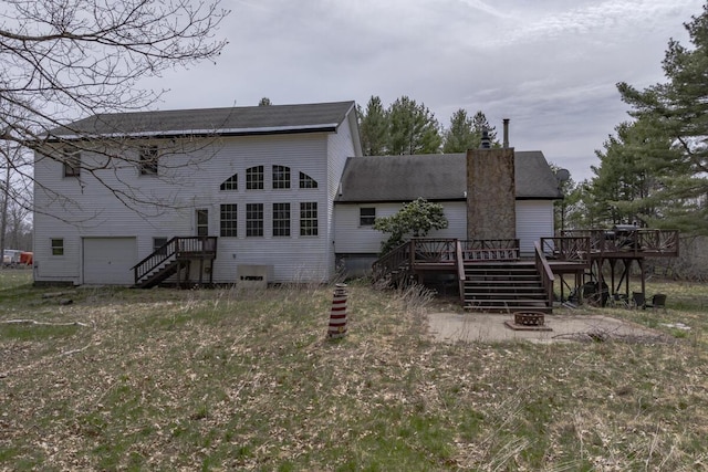 rear view of property with a fire pit, stairway, a chimney, a deck, and an attached garage