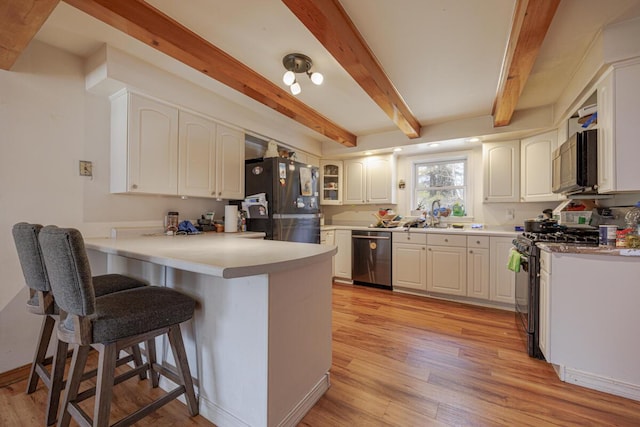 kitchen with a kitchen breakfast bar, appliances with stainless steel finishes, light wood-style floors, and a peninsula