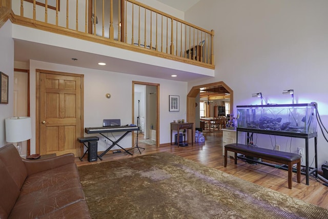 living area with arched walkways, a high ceiling, and wood finished floors