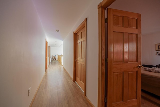 hall with baseboards and light wood finished floors