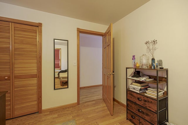 corridor with light wood-style flooring and baseboards