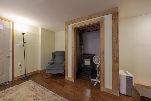 living area featuring a wood stove, baseboards, and wood-type flooring