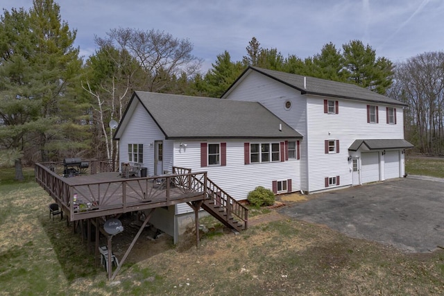 back of property featuring aphalt driveway, an attached garage, a shingled roof, a wooden deck, and stairs