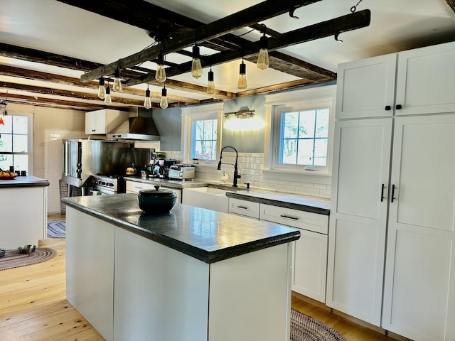 286 Lexington Rd, Kingfield, ME 04947 - kitchen featuring a sink, dark countertops, wall chimney range hood, light wood-style floors, and tasteful backsplash