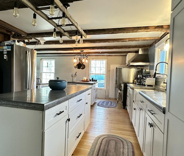 286 Lexington Rd, Kingfield, ME 04947 - kitchen with beam ceiling, wall chimney range hood, light wood-style flooring, white cabinetry, and freestanding refrigerator