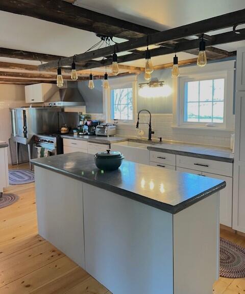 286 Lexington Rd, Kingfield, ME 04947 - kitchen featuring a sink, light wood finished floors, white cabinets, a kitchen island, and beamed ceiling