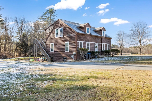 view of side of home with stairway and a lawn