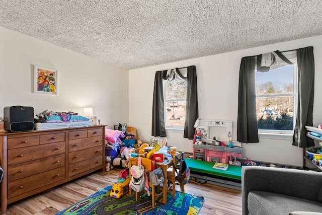 rec room featuring light wood-style flooring, a wealth of natural light, and a textured ceiling