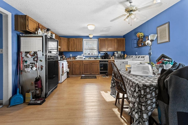 kitchen with light wood-type flooring, light countertops, brown cabinetry, washer and dryer, and stainless steel appliances