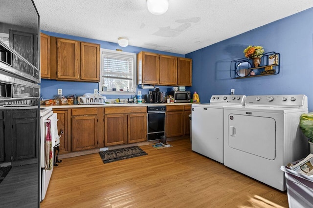 kitchen with washing machine and clothes dryer, stainless steel microwave, light countertops, brown cabinets, and light wood-style flooring