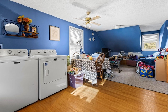 laundry area featuring a textured ceiling, laundry area, light wood-type flooring, and washer and clothes dryer