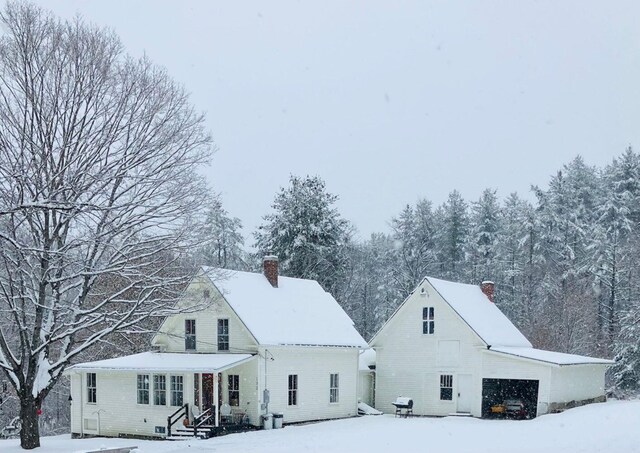 snow covered house with a garage and a chimney