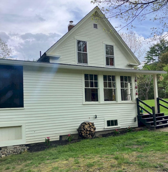 view of home's exterior with a chimney and a yard