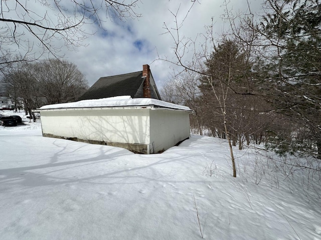 view of snow covered exterior with a chimney