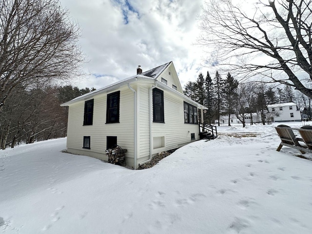 view of snow covered exterior featuring a chimney