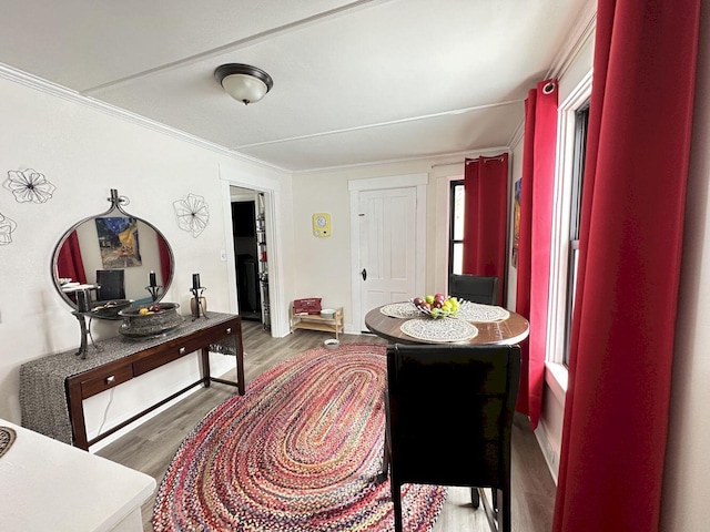 dining space with wood finished floors and crown molding