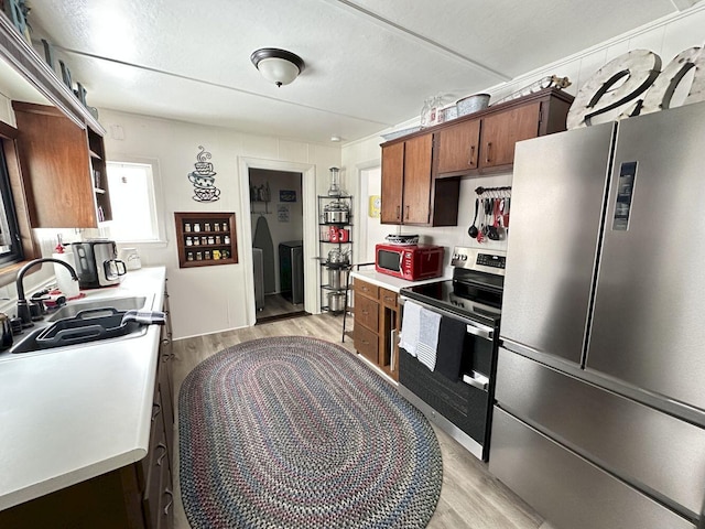 kitchen featuring a sink, appliances with stainless steel finishes, light countertops, and light wood finished floors