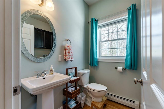 half bath featuring a sink, a baseboard heating unit, and toilet