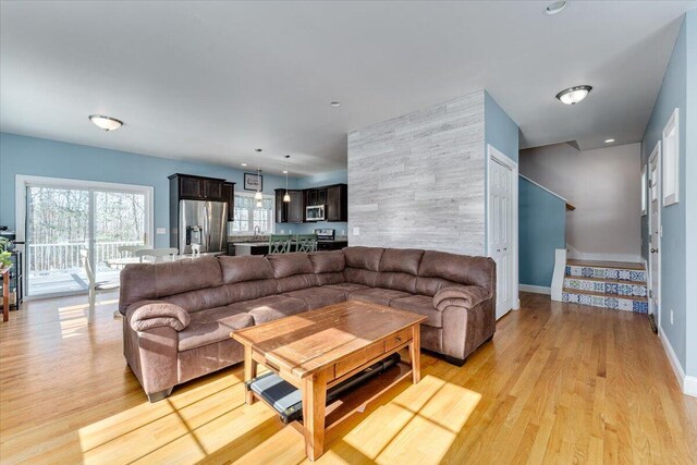 living room featuring recessed lighting, stairway, light wood-style flooring, and baseboards