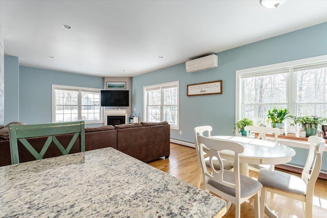 dining area with baseboard heating, an AC wall unit, a fireplace, and a healthy amount of sunlight