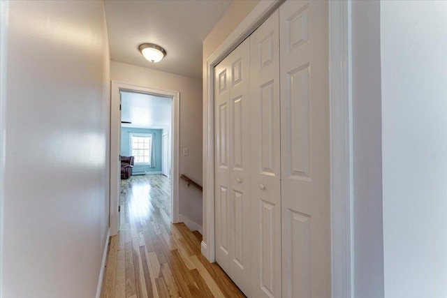 hall with light wood-style flooring and baseboards