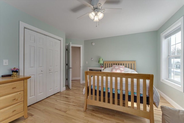 bedroom with a closet, a ceiling fan, light wood-type flooring, and baseboards