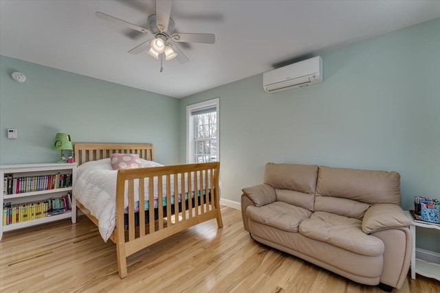 bedroom featuring ceiling fan, baseboards, wood finished floors, and a wall unit AC