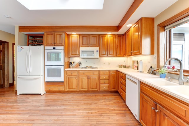 189 Mills Rd, Kennebunkport, ME 04046 - kitchen featuring light countertops, light wood-type flooring, a skylight, white appliances, and backsplash