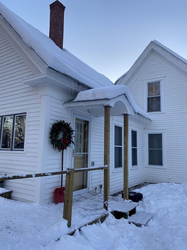 view of snow covered exterior with a chimney