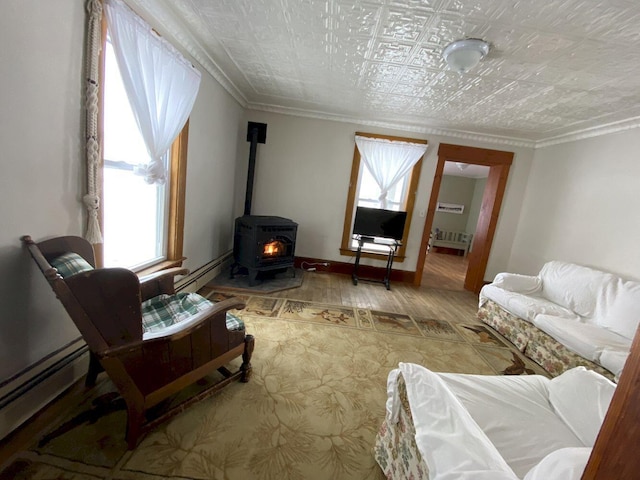 living area featuring crown molding, a wood stove, baseboards, and baseboard heating