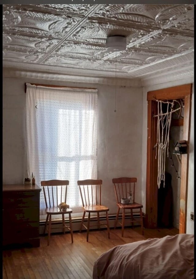 sitting room with a wealth of natural light, an ornate ceiling, baseboard heating, and hardwood / wood-style floors