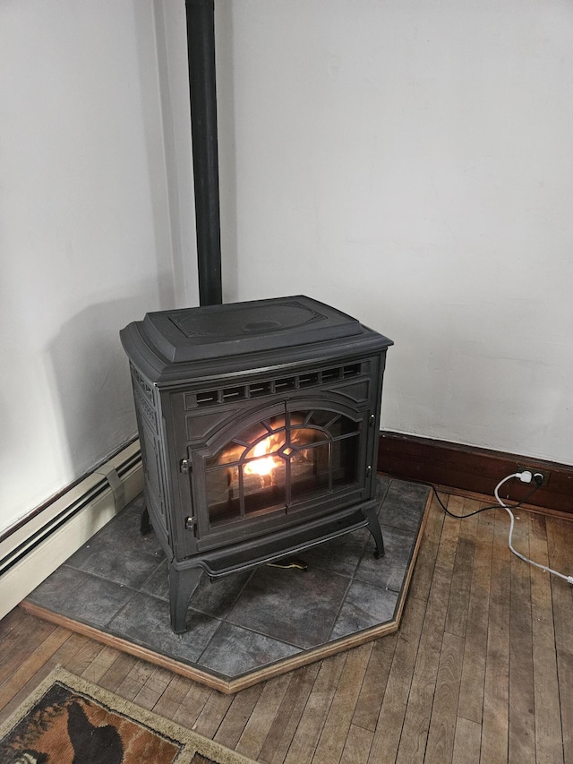 interior details with a baseboard radiator, a wood stove, and wood finished floors