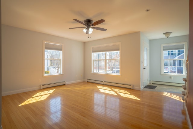 empty room featuring a baseboard heating unit, a healthy amount of sunlight, and hardwood / wood-style floors