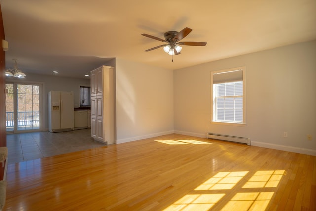 empty room featuring light wood-type flooring, a baseboard heating unit, baseboards, and ceiling fan with notable chandelier