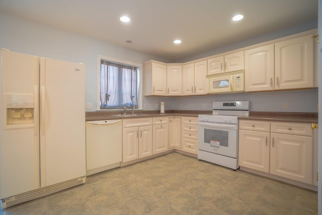 kitchen featuring white appliances, dark countertops, recessed lighting, and a sink