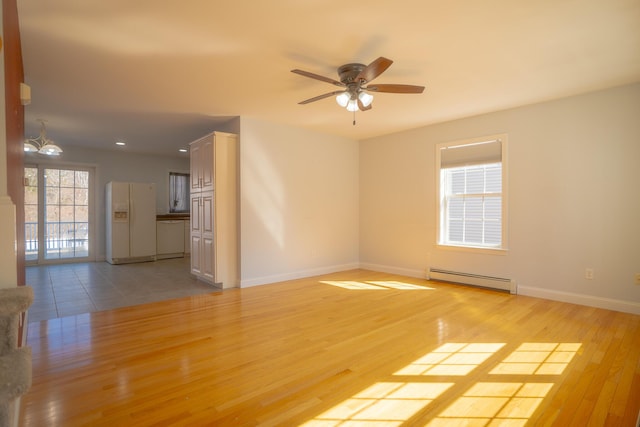 unfurnished room featuring light wood-style flooring, ceiling fan with notable chandelier, baseboards, and baseboard heating